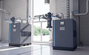 This is an image of an Atlas Copco air compressor. It is a grey box with white writing across the top and a blue line running vertically. Compressed air systems are vital when running complex machinery and systems. Did you know you there are easy steps to make your machine run more energy efficient and therefore saving money?